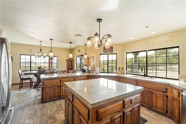 kitchen featuring hardwood / wood-style flooring, a center island, an inviting chandelier, and sink