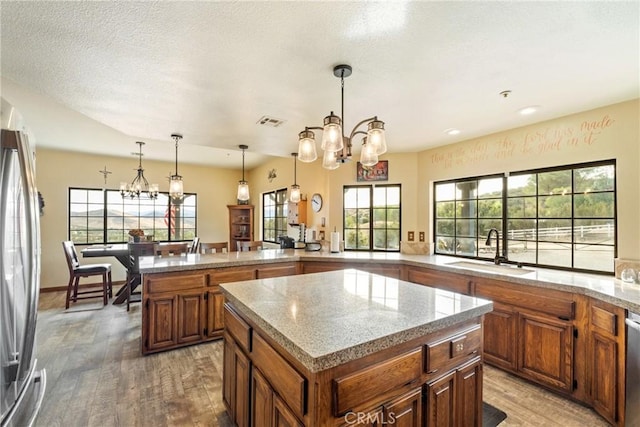 6535 Juniper Crest Rd, Agua Dulce, CA 91390 - kitchen featuring a chandelier, appliances with stainless steel finishes, brown cabinets, a kitchen island, and a textured ceiling