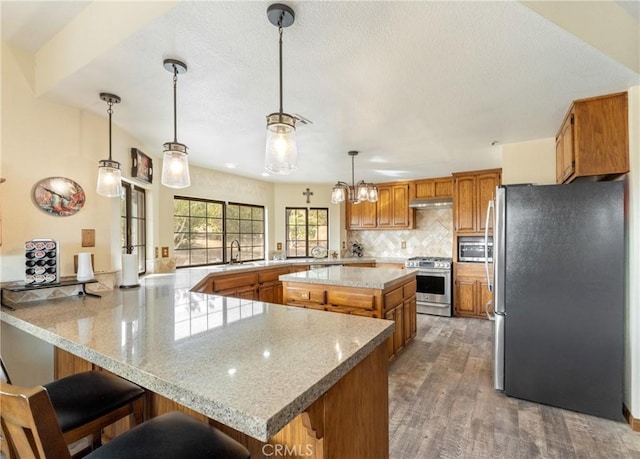 6535 Juniper Crest Rd, Agua Dulce, CA 91390 - kitchen featuring stainless steel appliances, a peninsula, brown cabinetry, tasteful backsplash, and a textured ceiling