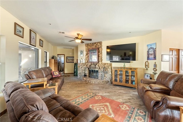 living room with hardwood / wood-style floors, ceiling fan, and a fireplace