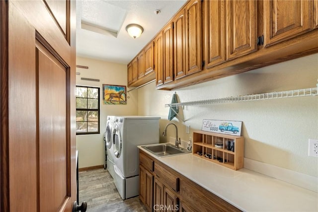 laundry area with cabinets, light wood-type flooring, separate washer and dryer, and sink