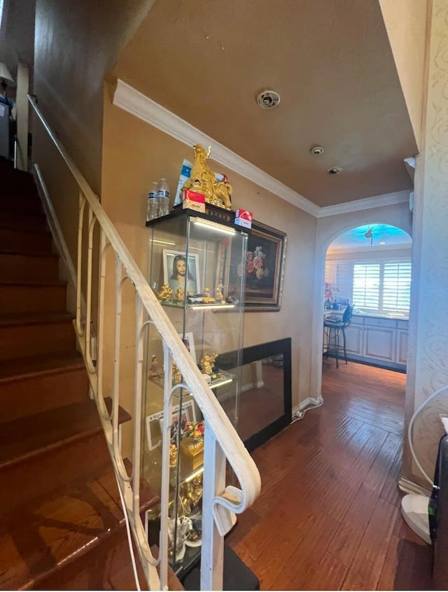 stairs with crown molding and wood-type flooring