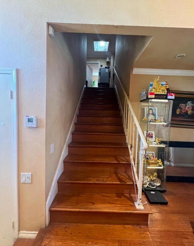 stairway featuring crown molding and wood-type flooring