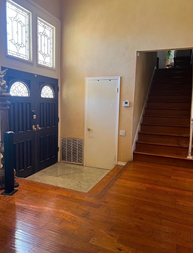 foyer featuring hardwood / wood-style flooring and a towering ceiling