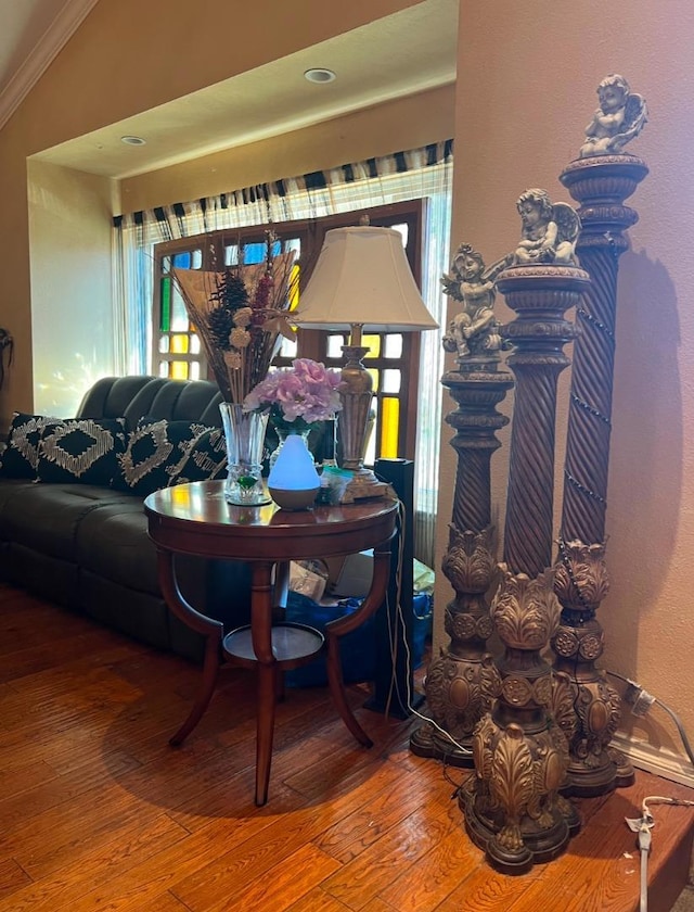 living room featuring crown molding, wood-type flooring, and vaulted ceiling