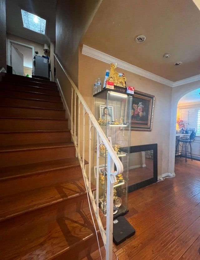 staircase with a skylight, crown molding, and wood-type flooring