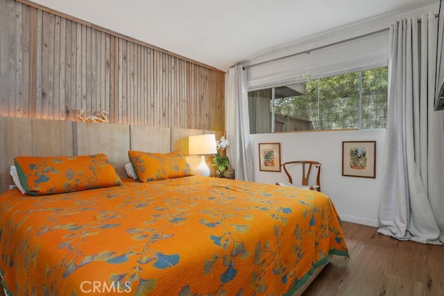 bedroom with hardwood / wood-style floors and lofted ceiling