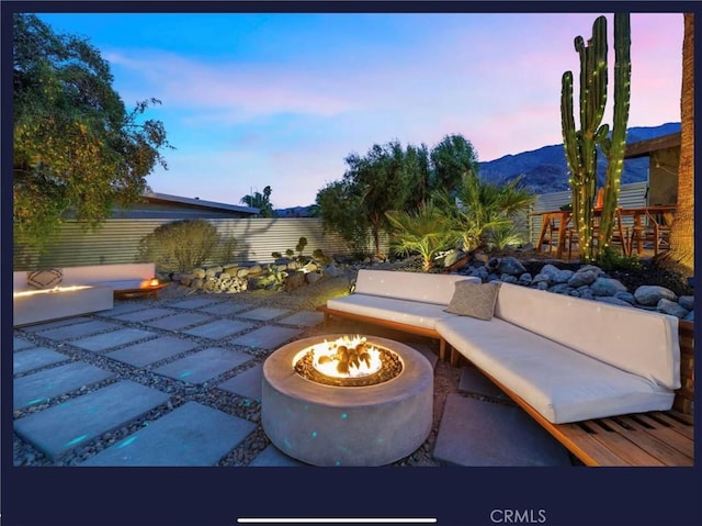 patio terrace at dusk with a mountain view and an outdoor living space with a fire pit