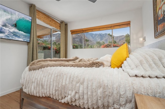 bedroom featuring a mountain view, access to outside, and hardwood / wood-style flooring