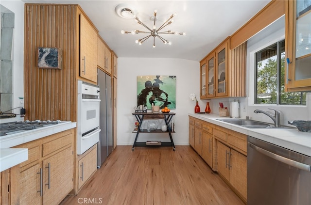 kitchen with a notable chandelier, light wood-type flooring, white appliances, and sink