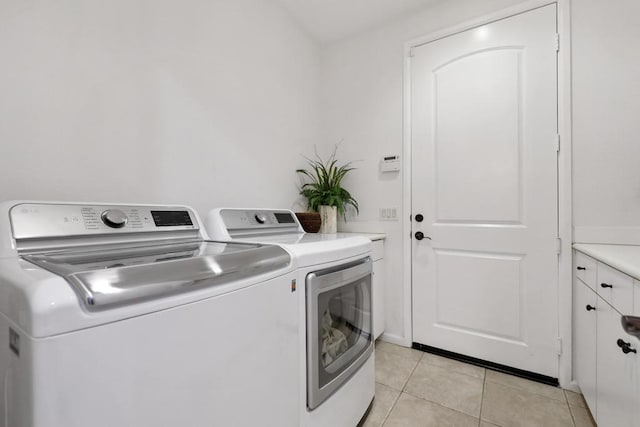 clothes washing area with cabinets, independent washer and dryer, and light tile patterned floors