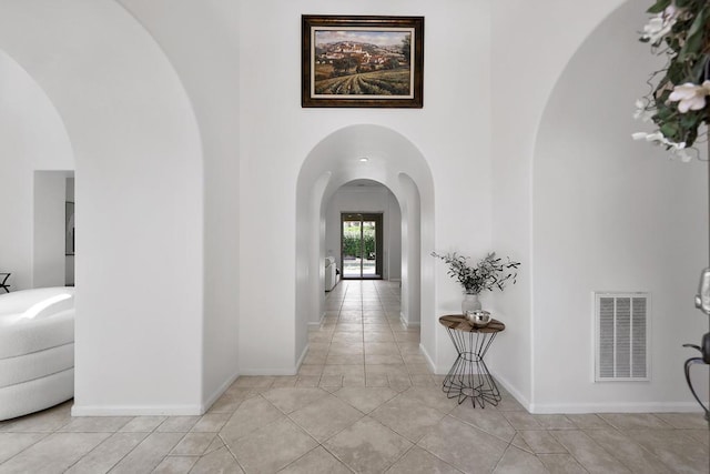 corridor with light tile patterned floors and a high ceiling