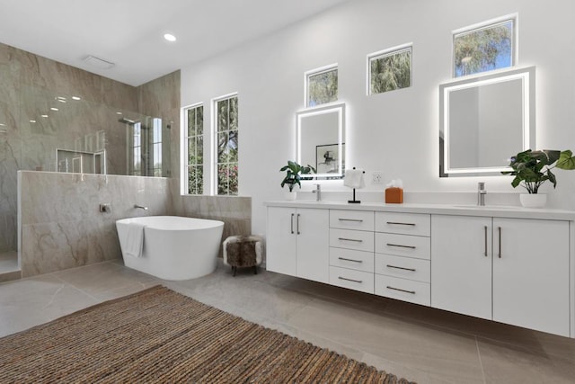 bathroom featuring tile patterned flooring, vanity, a tile shower, and a wealth of natural light