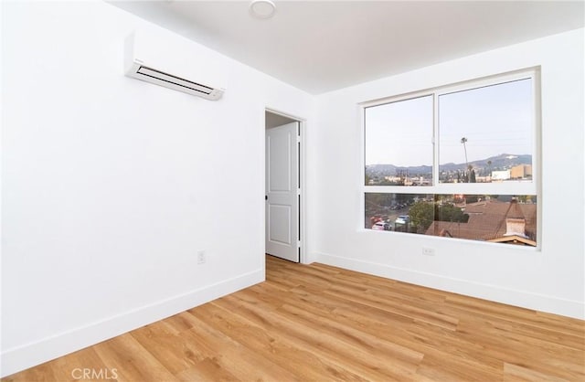 unfurnished room with a wall mounted air conditioner and hardwood / wood-style flooring