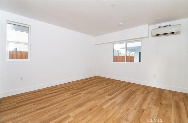 empty room featuring light wood-type flooring and an AC wall unit