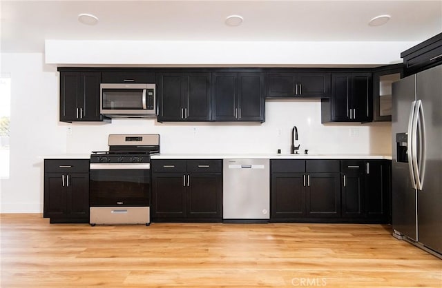 kitchen with appliances with stainless steel finishes, light wood-type flooring, and sink