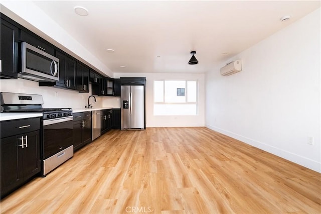 kitchen featuring a wall unit AC, stainless steel appliances, and light hardwood / wood-style floors