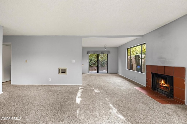 unfurnished living room with heating unit, carpet floors, and a tile fireplace