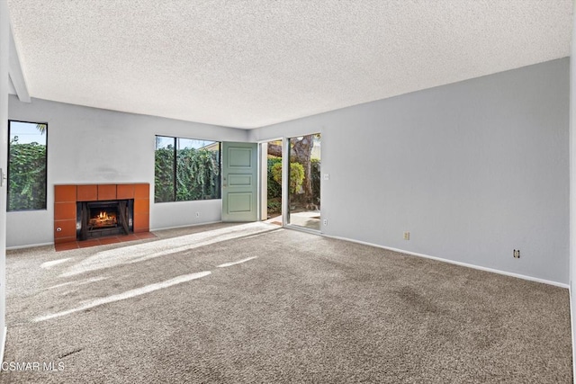 unfurnished living room with a textured ceiling, carpet, and a tile fireplace