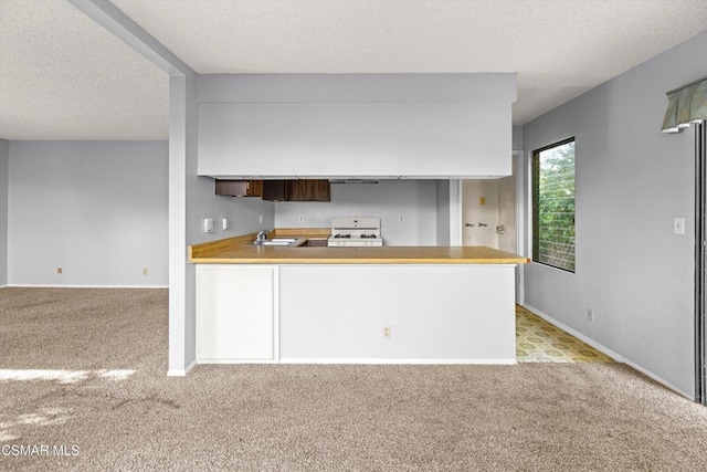 kitchen featuring kitchen peninsula, white stove, sink, a textured ceiling, and light carpet