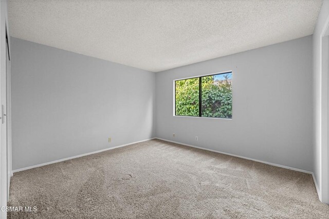 carpeted spare room featuring a textured ceiling