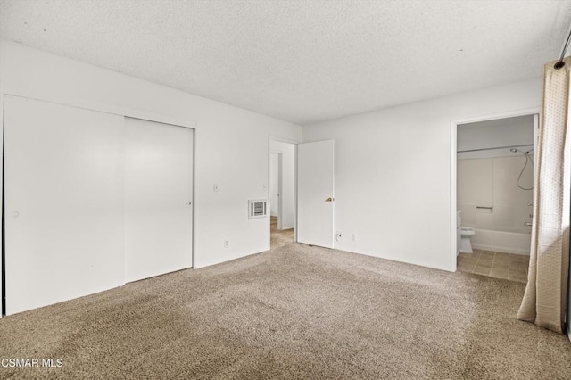 unfurnished bedroom with carpet floors, a closet, connected bathroom, and a textured ceiling