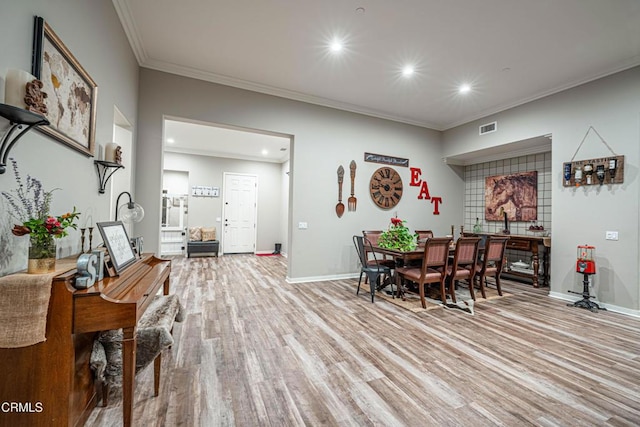 dining room with crown molding and light hardwood / wood-style floors