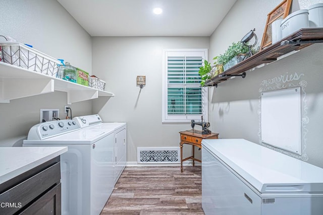 clothes washing area with washing machine and clothes dryer and light wood-type flooring