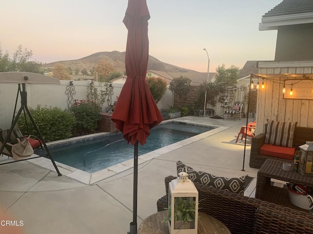 pool at dusk with a patio and a mountain view