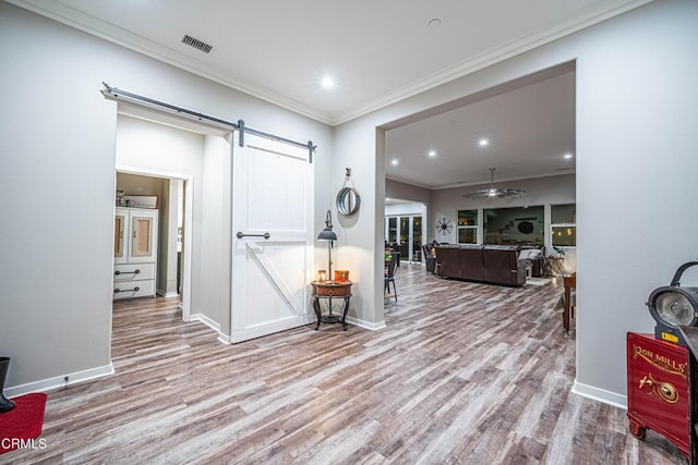 hall featuring crown molding, a barn door, and light wood-type flooring