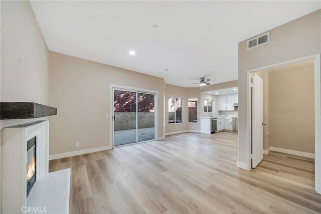 unfurnished living room featuring ceiling fan and light wood-type flooring