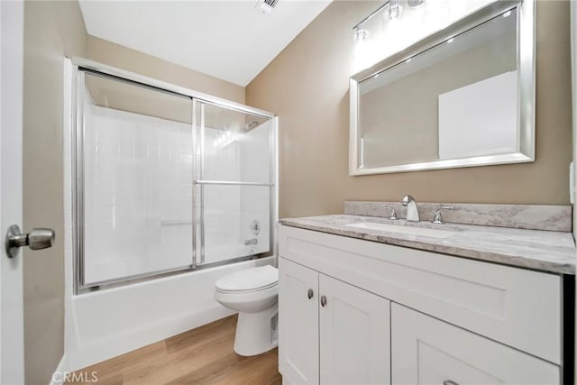 full bathroom with hardwood / wood-style flooring, vanity, toilet, and enclosed tub / shower combo