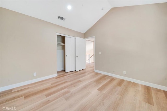 unfurnished bedroom with a closet, vaulted ceiling, and light wood-type flooring