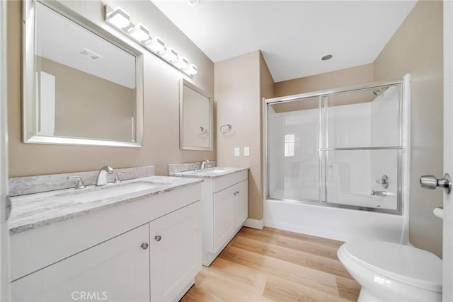 full bathroom featuring combined bath / shower with glass door, hardwood / wood-style floors, vanity, and toilet