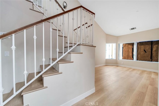 stairway with wood-type flooring and lofted ceiling