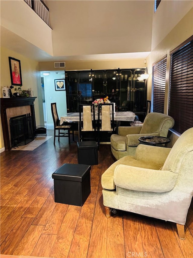 living room with hardwood / wood-style flooring, a fireplace, and a high ceiling