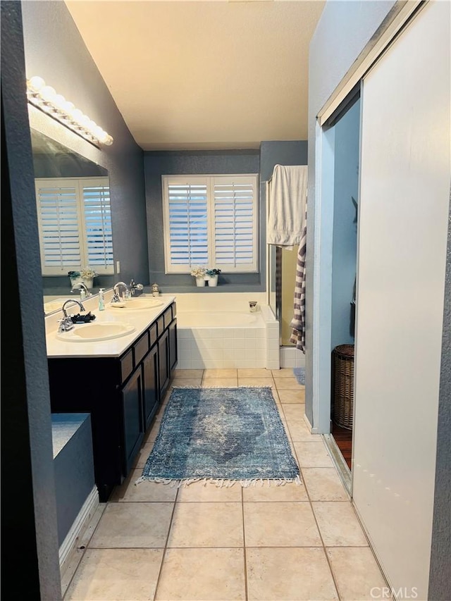 bathroom featuring tile patterned flooring, vanity, and tiled tub