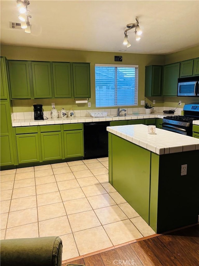 kitchen featuring green cabinets, tile countertops, a center island, and black appliances