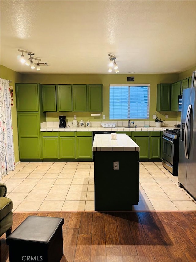 kitchen with a center island, stainless steel appliances, light hardwood / wood-style flooring, and green cabinetry