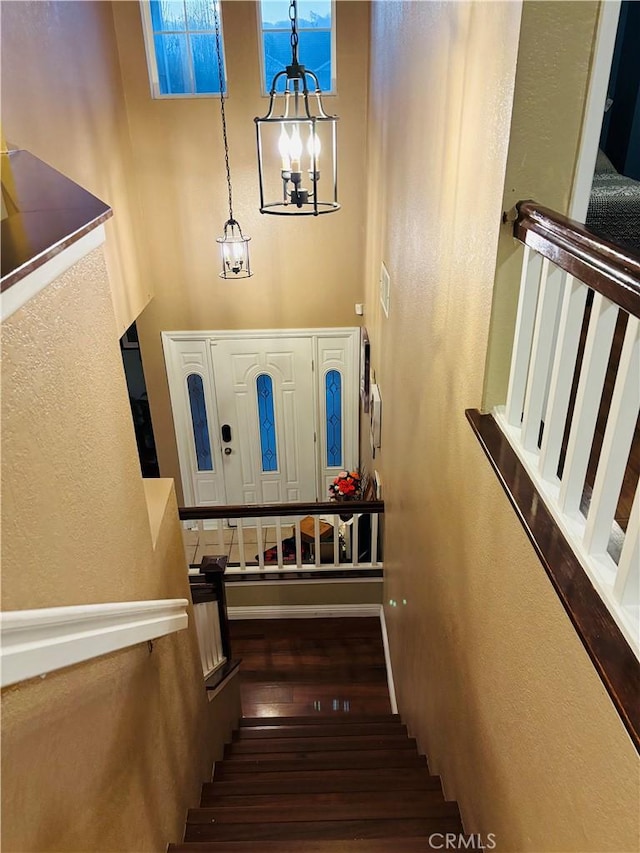 stairs with hardwood / wood-style floors and a chandelier