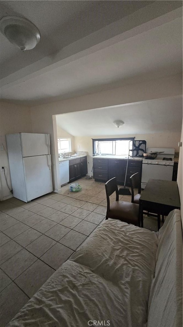 tiled bedroom featuring white fridge and lofted ceiling