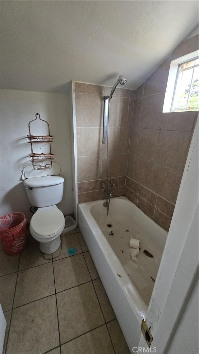 bathroom with tile patterned floors, vaulted ceiling, a textured ceiling, toilet, and tiled shower / bath