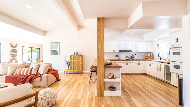 kitchen featuring plenty of natural light, light wood-type flooring, white cabinetry, and tasteful backsplash