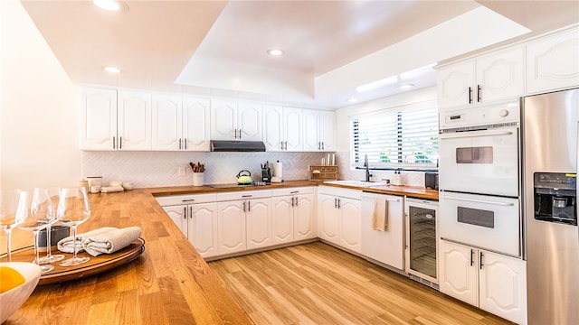 kitchen featuring wood counters, white cabinetry, white appliances, and beverage cooler