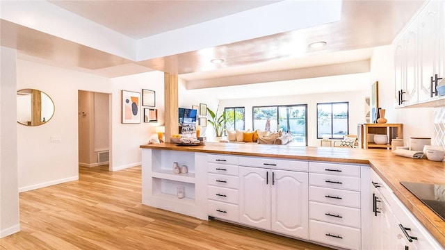 kitchen with white cabinets, wooden counters, light hardwood / wood-style floors, and kitchen peninsula