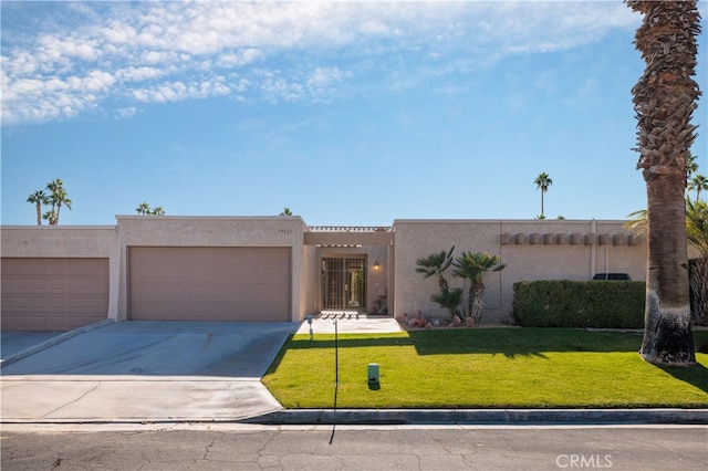 pueblo-style house featuring a garage and a front lawn