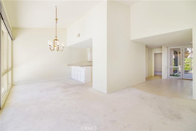 unfurnished room with light carpet, a towering ceiling, and a notable chandelier