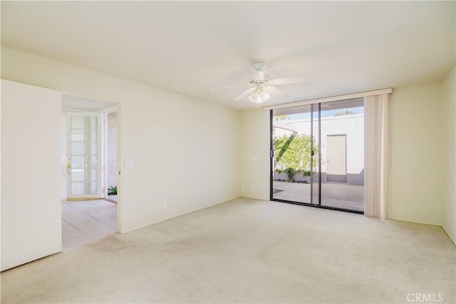 spare room with ceiling fan, a wall of windows, and light colored carpet