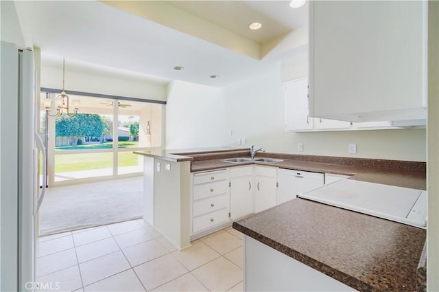 kitchen with a notable chandelier, sink, white appliances, light carpet, and white cabinets