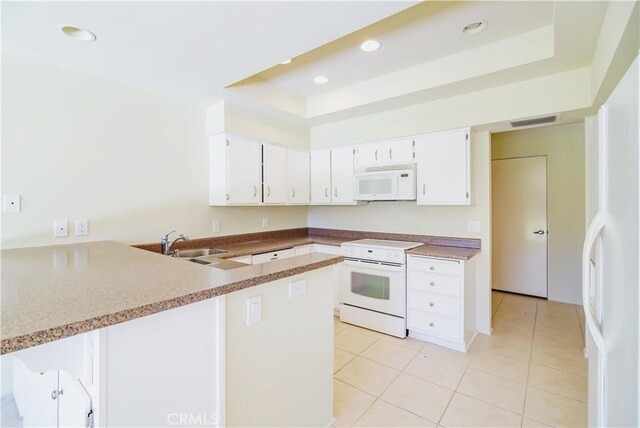 kitchen with white cabinetry, white appliances, a raised ceiling, and kitchen peninsula